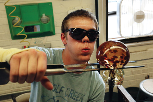 Evin Barber, a sophomore in ceramic engineering, cools down a glass paperweight while using jacks to create a line for the glass to separate from the solid stainless steel rod, known as a punty.