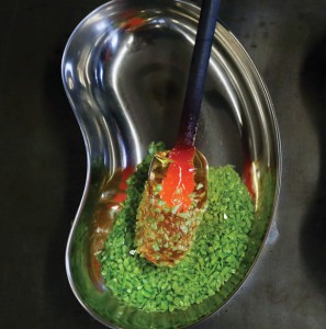 Molten glass on the end of a rod is fused with green glass granulates