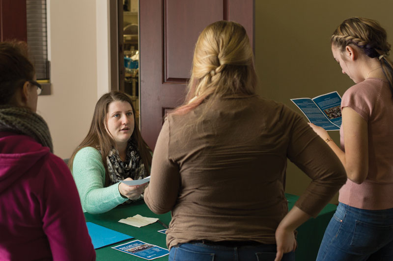 Cailey Baker recruits students to work with the Miner Phonathon during an event in the Hasselmann Alumni House.