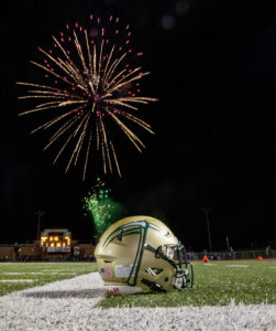 Missouri S&amp;T football helmet sits on the football field with fireworks in the dark sky behind.